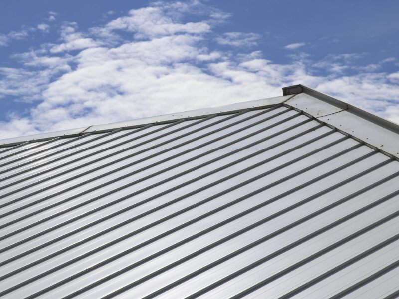 Metal sheet roof and slope with clouds and blue sky background.