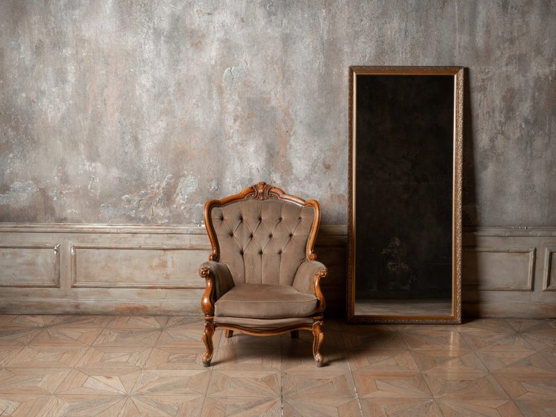 old chair and a mirror on the background of vintage wall